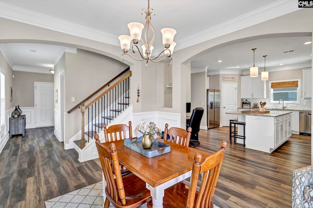 dining room featuring arched walkways, dark wood-type flooring, stairway, and wainscoting