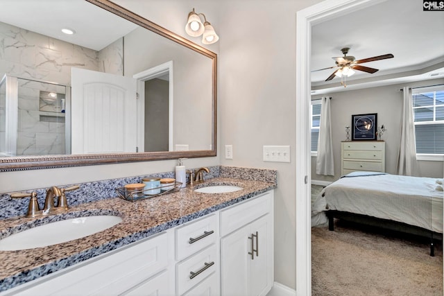 ensuite bathroom featuring double vanity, ceiling fan, walk in shower, and a sink