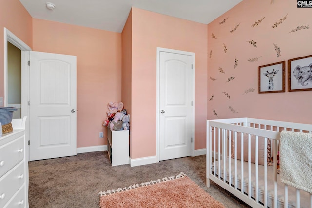 carpeted bedroom featuring a crib and baseboards