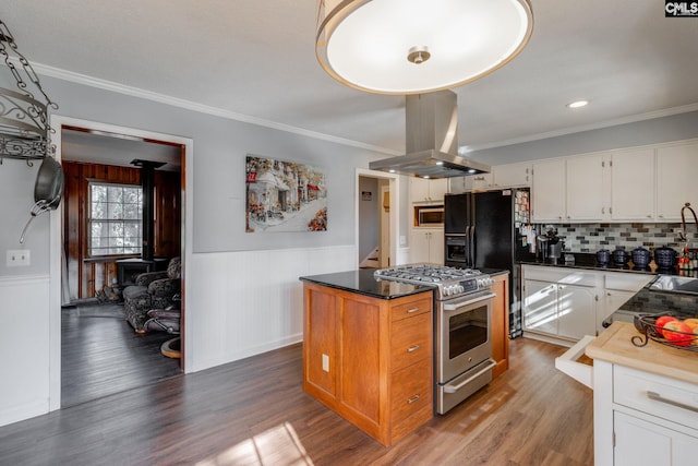 kitchen with white cabinets, island range hood, stainless steel appliances, and wainscoting