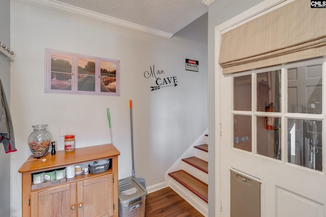 interior space featuring baseboards, ornamental molding, a textured ceiling, and wood finished floors