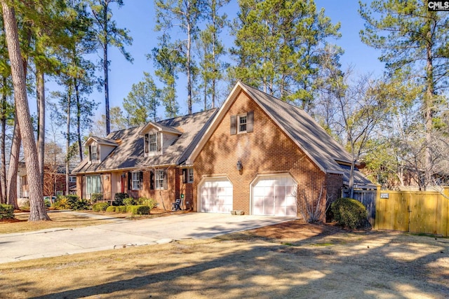 new england style home with driveway, a garage, fence, and brick siding