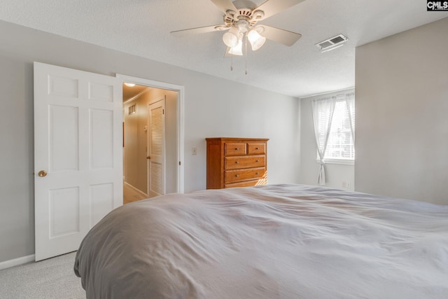 carpeted bedroom featuring ceiling fan, a textured ceiling, visible vents, and baseboards