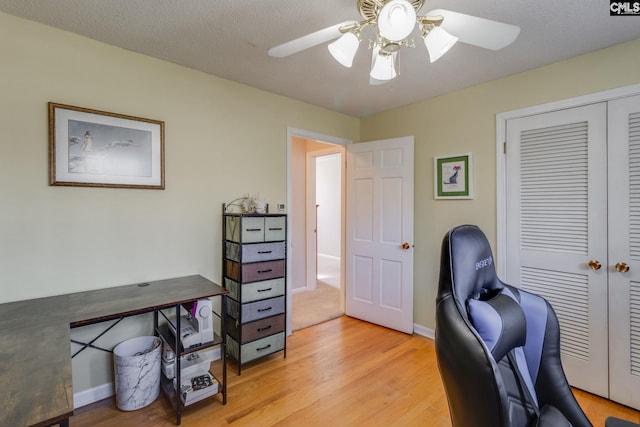 office featuring ceiling fan, light wood finished floors, a textured ceiling, and baseboards