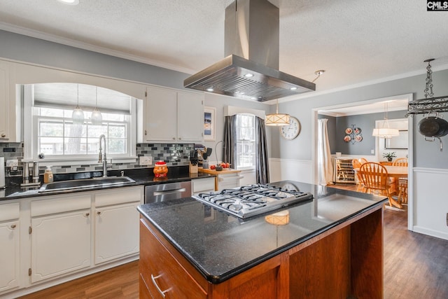 kitchen with stainless steel appliances, dark countertops, a sink, and island range hood