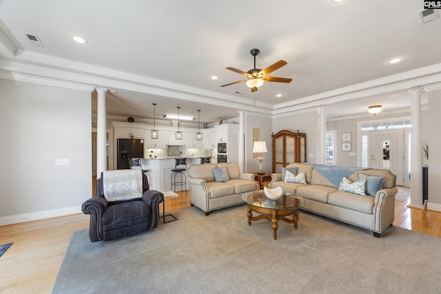 living room with baseboards, a tray ceiling, decorative columns, and crown molding