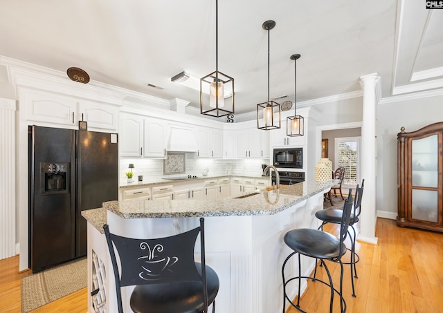 kitchen featuring crown molding, light wood finished floors, decorative backsplash, white cabinetry, and black appliances