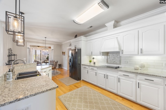 kitchen featuring visible vents, custom exhaust hood, black appliances, white cabinetry, and a sink