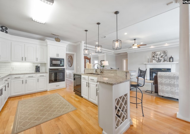 kitchen with decorative backsplash, a glass covered fireplace, a sink, black appliances, and a kitchen breakfast bar