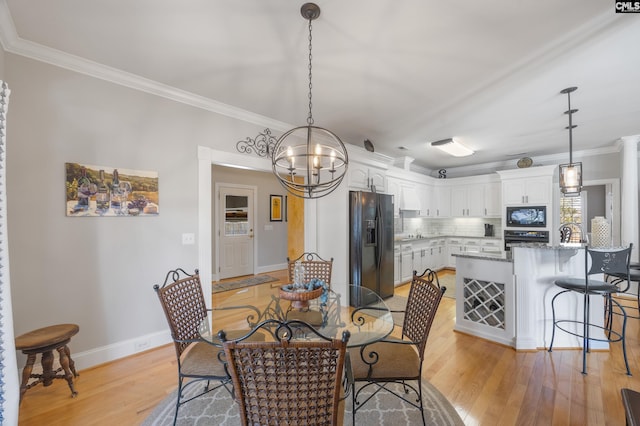 dining room featuring light wood-type flooring, a notable chandelier, and crown molding