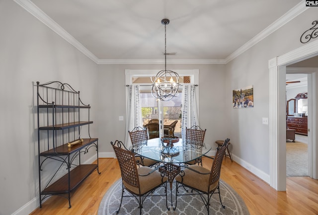 dining area with light wood finished floors, crown molding, baseboards, and a notable chandelier