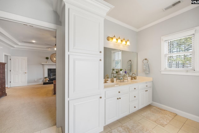 bathroom featuring double vanity, visible vents, crown molding, a fireplace, and a sink