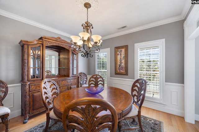 dining space featuring light wood-type flooring, wainscoting, and visible vents