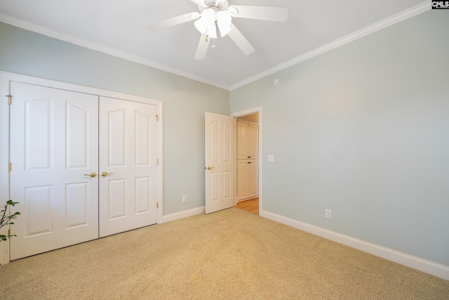 unfurnished bedroom with ceiling fan, baseboards, ornamental molding, a closet, and carpet