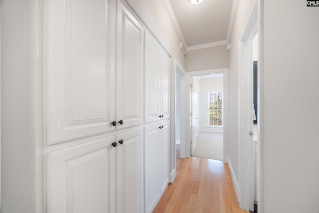 hall with baseboards, light wood-type flooring, and crown molding