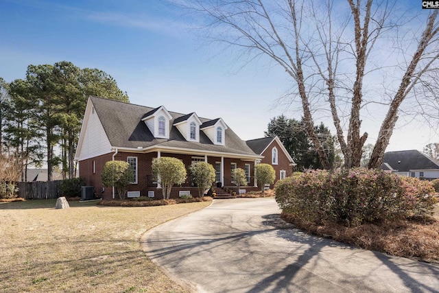 new england style home featuring central AC, brick siding, a front yard, and fence