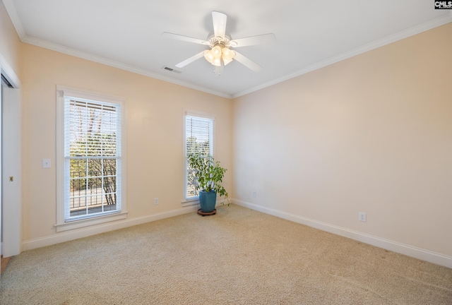 carpeted spare room featuring baseboards, plenty of natural light, visible vents, and crown molding