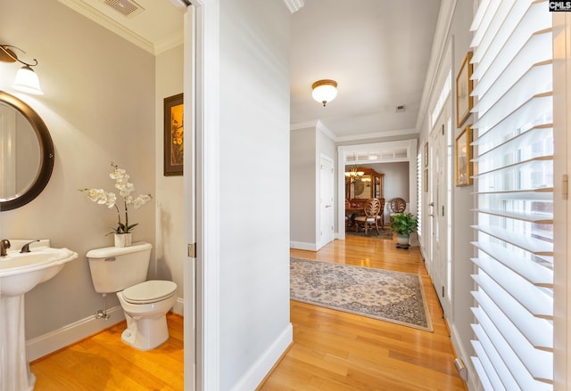 hallway featuring baseboards, ornamental molding, and wood finished floors