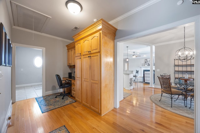 office area with light wood-style flooring, a fireplace, attic access, and crown molding