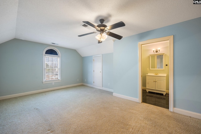 unfurnished bedroom with carpet, lofted ceiling, visible vents, a textured ceiling, and baseboards