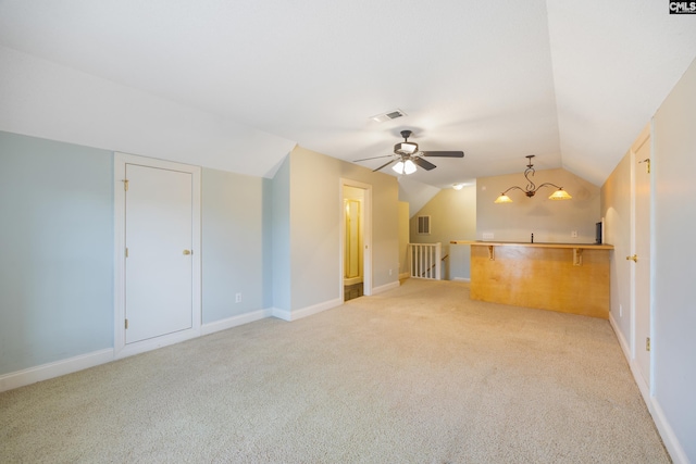 unfurnished living room with lofted ceiling, baseboards, visible vents, and light colored carpet