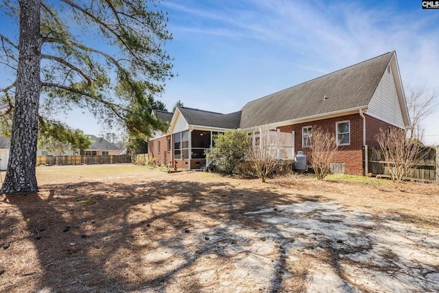 back of property featuring brick siding, fence, and a sunroom