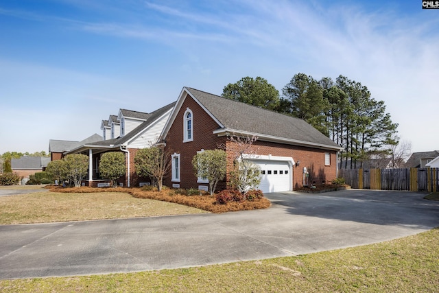 view of side of home with driveway, a garage, fence, a yard, and brick siding