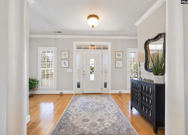 foyer entrance with plenty of natural light, ornamental molding, and wood finished floors