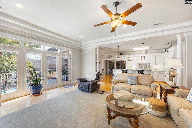 living area with recessed lighting, visible vents, a ceiling fan, ornamental molding, and a raised ceiling