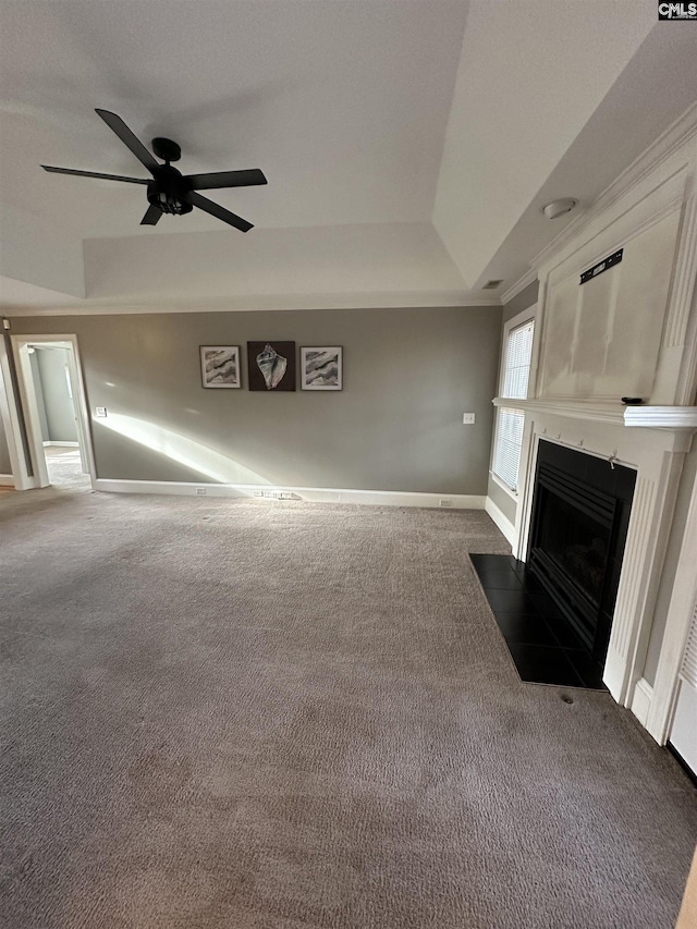 unfurnished living room with baseboards, a raised ceiling, a fireplace with flush hearth, ceiling fan, and carpet floors