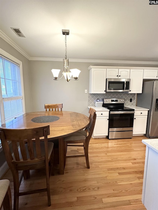 kitchen with visible vents, light wood-style floors, white cabinetry, appliances with stainless steel finishes, and crown molding