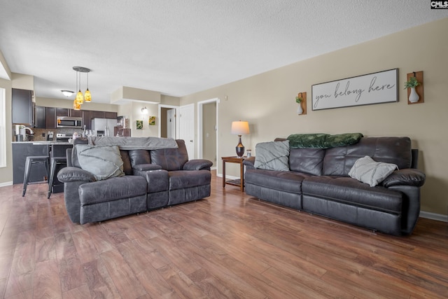 living area with a textured ceiling, baseboards, and wood finished floors