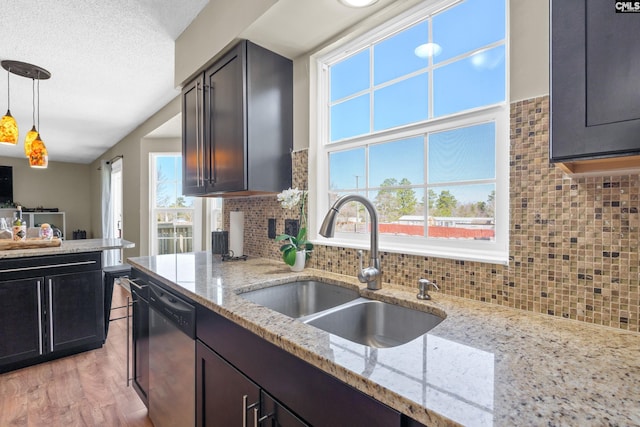 kitchen featuring pendant lighting, decorative backsplash, a sink, a textured ceiling, and dishwasher