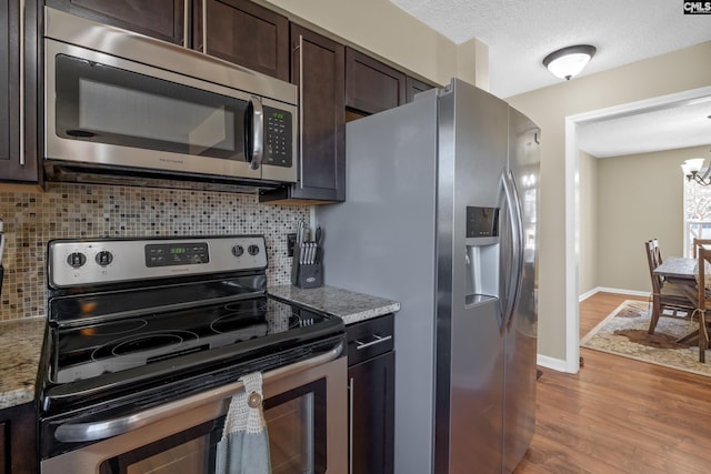 kitchen with dark brown cabinetry, tasteful backsplash, baseboards, appliances with stainless steel finishes, and light wood-style floors