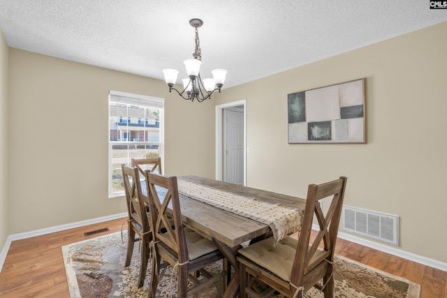 dining room featuring a textured ceiling, wood finished floors, visible vents, and baseboards