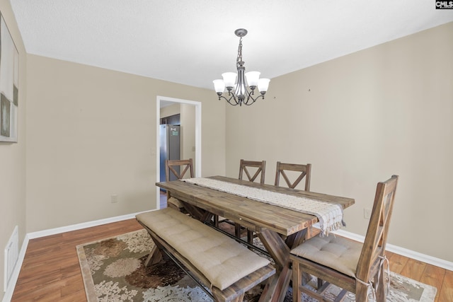 dining area with light wood-style floors, visible vents, baseboards, and a notable chandelier