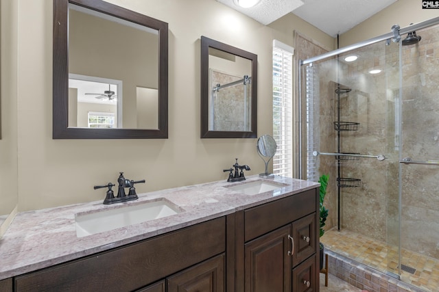 bathroom featuring double vanity, a shower stall, ceiling fan, and a sink