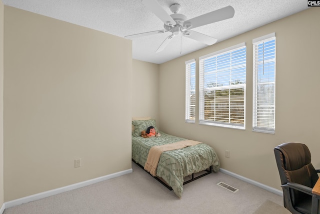 carpeted bedroom with a textured ceiling, ceiling fan, visible vents, and baseboards
