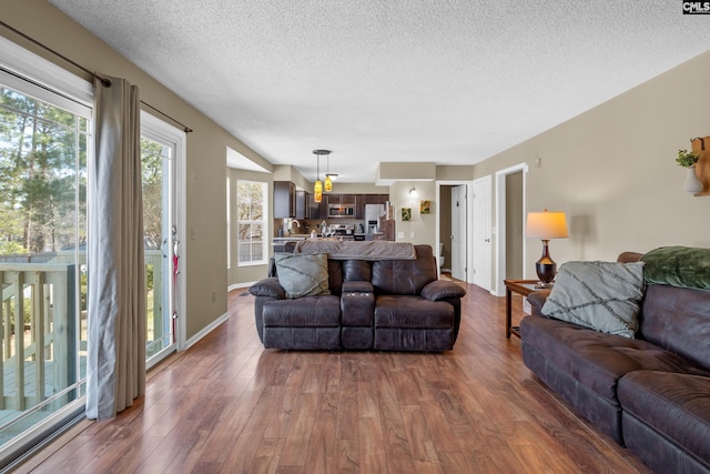 living room with a textured ceiling, baseboards, and wood finished floors