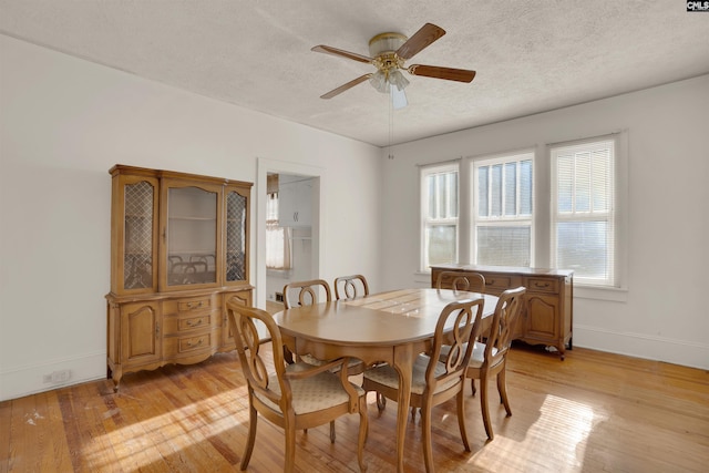 dining room featuring a textured ceiling, baseboards, a ceiling fan, and light wood-style floors