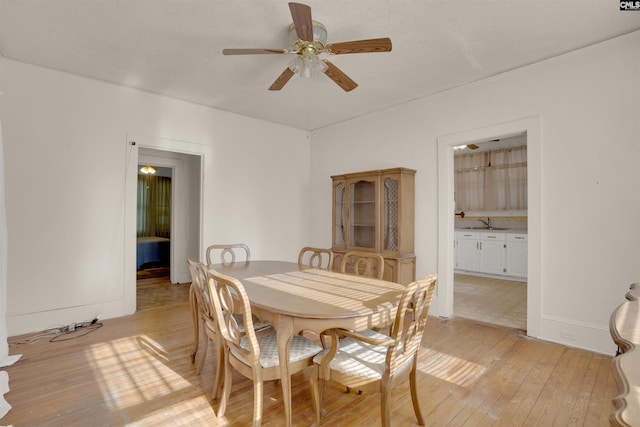 dining space with ceiling fan, a textured ceiling, light wood-style flooring, and baseboards