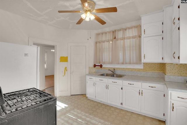 kitchen with a sink, light countertops, freestanding refrigerator, light floors, and gas range