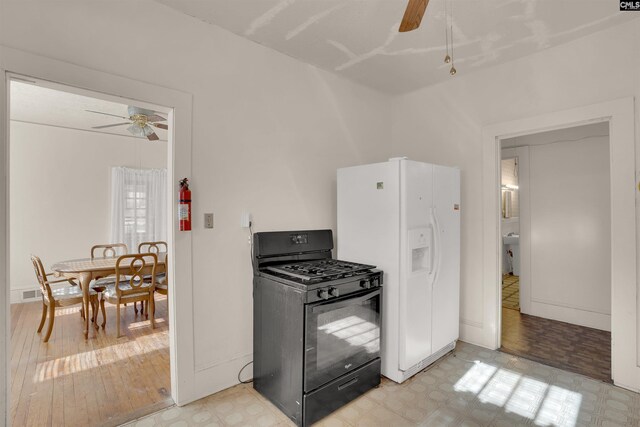 kitchen with white fridge with ice dispenser, light floors, a ceiling fan, and black gas range oven