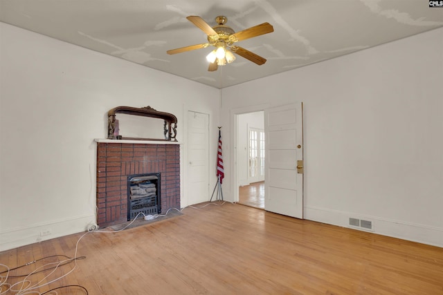 unfurnished living room featuring baseboards, visible vents, ceiling fan, wood finished floors, and a fireplace