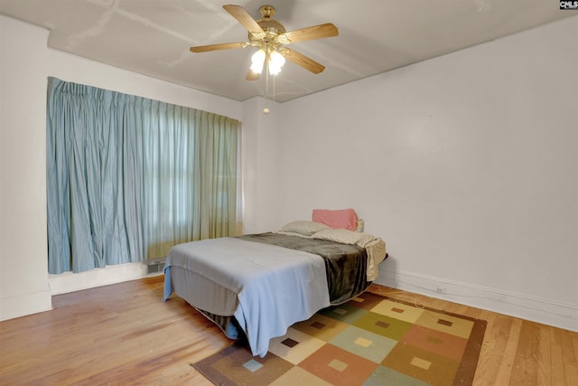 bedroom featuring ceiling fan, wood finished floors, visible vents, and baseboards