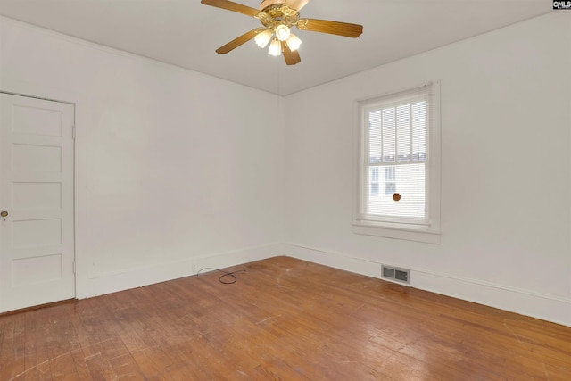 unfurnished room with a ceiling fan, wood-type flooring, visible vents, and baseboards