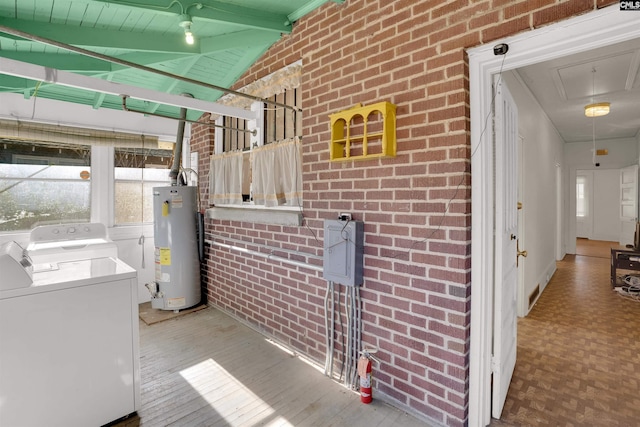 interior space featuring washer and clothes dryer, water heater, attic access, brick wall, and laundry area