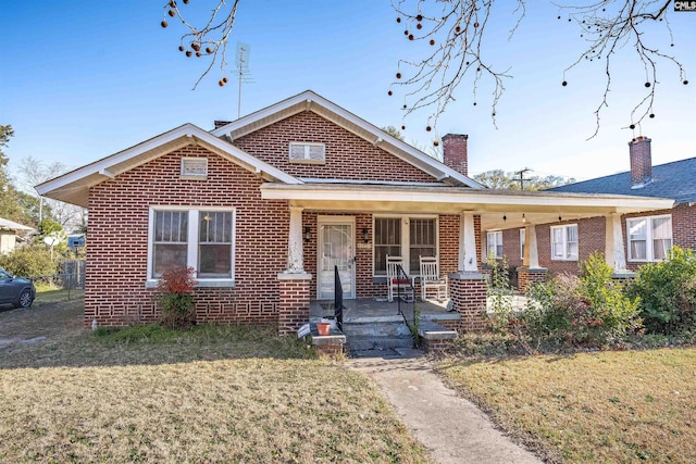 bungalow-style house with a front lawn, a porch, and brick siding