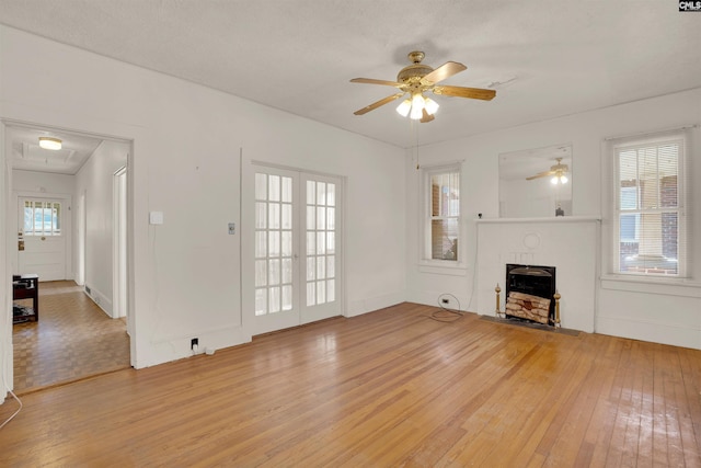 unfurnished living room featuring ceiling fan, baseboards, a fireplace with flush hearth, and light wood-style floors