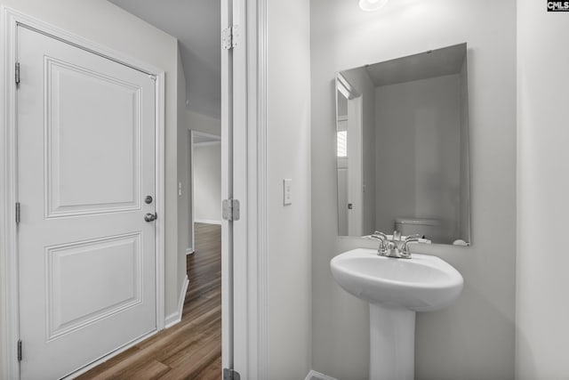 bathroom with a sink, wood finished floors, and baseboards